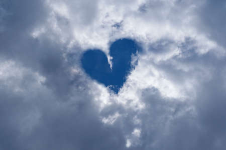 Heart shape on blue sky with clouds, background