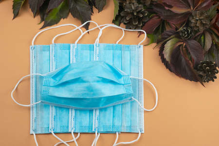 Autumn pandemic. Seasonal diseases. Disposable blue masks close-up on orange background with autumn...