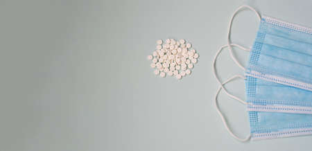 Protective disposable masks with pills on a light background. Medicine