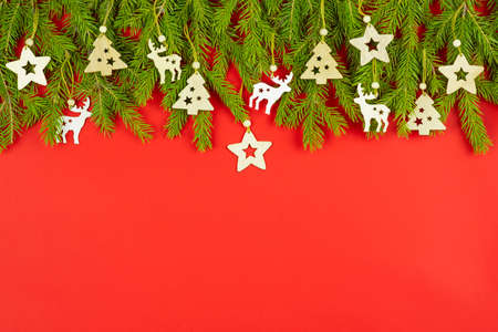 Spruce branches, christmas decorations on a red background. Flat lay, top view, copy space for your text. Christmas tree branches with toys on it. Christmas concept.の写真素材