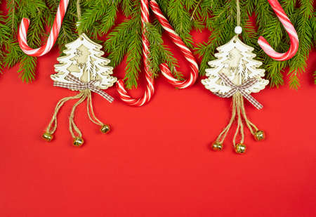 Christmas composition. Spruce branches, white christmas tree toys, red and white candy canes on a red background. Flat lay, top view, copy space for your textの写真素材
