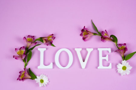 The word love on a pink background with alstroemeria flowers. Valentines Dayの写真素材