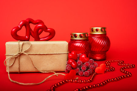 Gift in craft paper, red hearts with red candlesticks on a red background. St. Valentines Dayの写真素材