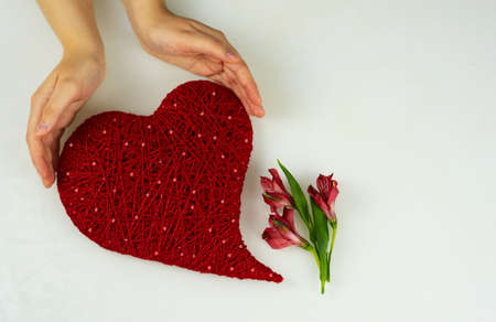 Heart of red threads of yarn in female hands on a light background. Valentines Dayの写真素材