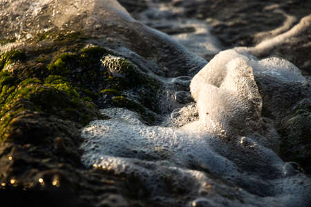 A small rock with moss and waves