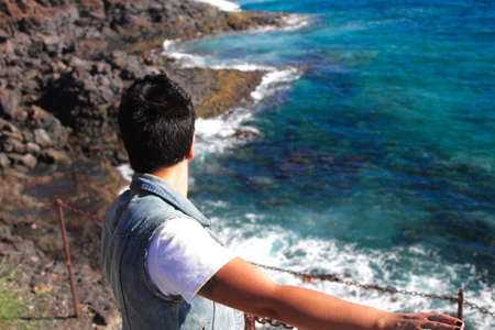 thoughtful girl looking at the sea from a cliffの写真素材