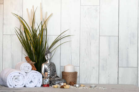 The silver statue of Buddha and spa essentials near the plant for aromatherapyの写真素材