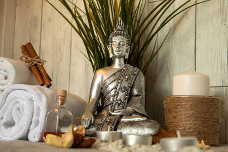The silver statue of Buddha and spa essentials near the plant for aromatherapyの写真素材