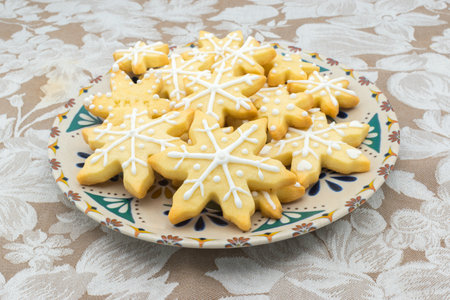 Plate with snowflake-shaped sugar icing Christmas cookies, on a tablecloth.の写真素材