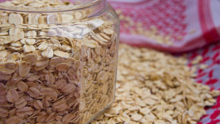 porridge crude is in the bottle on a cloth, flakes of porridge are scattered by a row, fabric of...