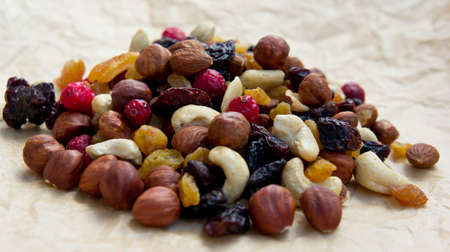 dried fruit lie on a light brown sheet of paper, all-sorts, nuts of different types, a fig, dry...