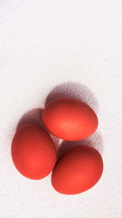 three eggs in a shell of red color lie on a light uneven surface,の写真素材
