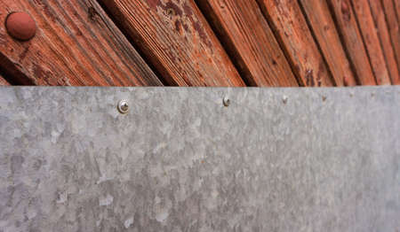 part of wooden gate of the orange and brown shades halved by the sheet of ironの写真素材