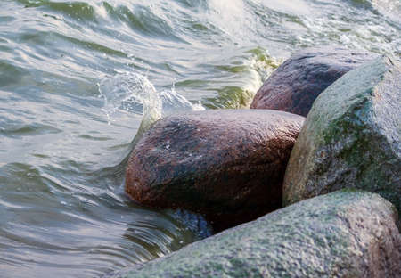 four large granite stones are located in the water, the water is in the form of a separate wave is broken against the stones, a light shot, the water background, a daylight, the waves are big and small,の写真素材