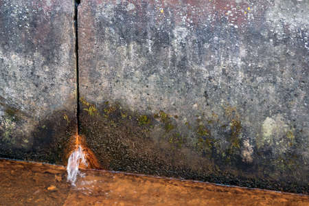 two concrete slabs of dirty gray color in spots, rusty water flows from the hole from below, in the foreground there is a liquid rusty from corrosion, a gloomy look, design, background, daylight,の写真素材