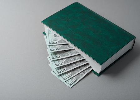 Hundred dollar bills in books looks like stairs on the grey background.の写真素材
