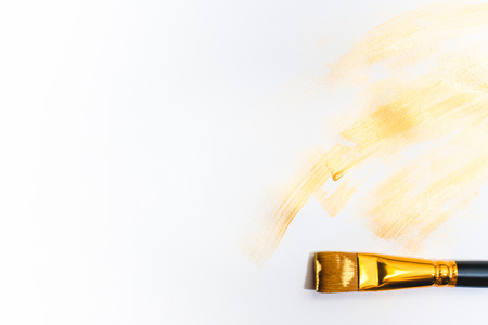 The golden strokes and a brush isolated on white background.の写真素材