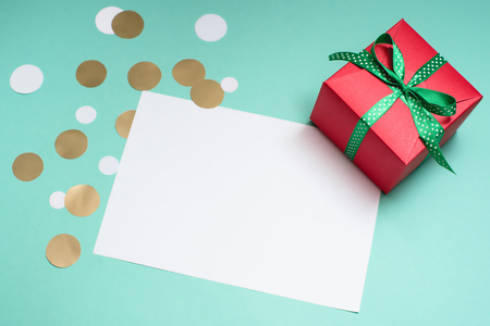 Decorated gift box, confetti and blank white sheet of paper.の写真素材