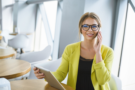 Business young woman in glasses works at a table in a cafe.の写真素材
