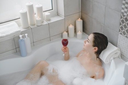 Young woman relaxes in a hot bath full of foam.の写真素材