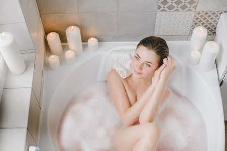 Young woman relaxes in a hot bath full of foam.の写真素材