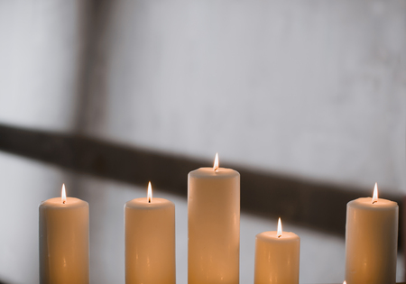 A group of different sized candles stands on a simple wooden table.