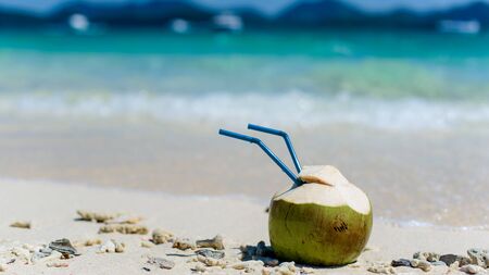 Drinking coconut with two straws on a tropical beach.