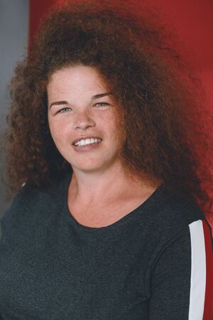 Portrait of ethnic redhead curly-haired woman with freckles.