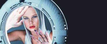 Attractive young blonde looks like in the porthole of a spaceship. Futuristic portrait.の写真素材