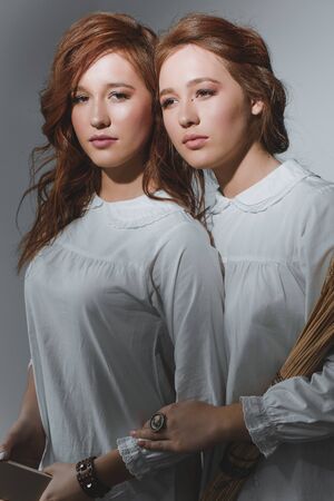 Portrait of two red-haired ethnic twin girls with a smartphone and a sheaf of wheat.の写真素材