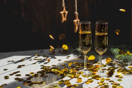 Two glasses of champagne in golden confetti.
