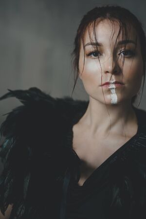 Young beautiful woman in a cape of black feathers in ethnic or tribal style.の写真素材