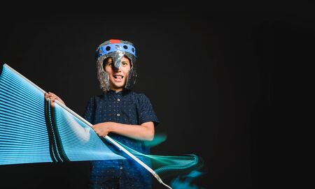 A kid with a lightsaber in his hands play in a superhero battle.