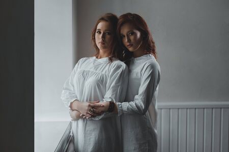Studio portrait of two red-haired twin girls.の写真素材