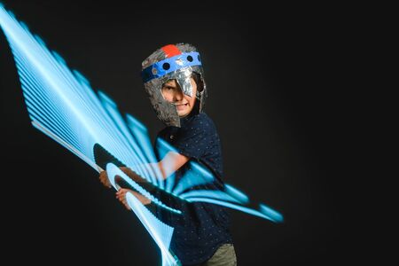 A kid with a light saber in his hands play in a superhero battle.