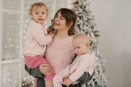 Family Christmas morning in a bright minimalistic living room near the Christmas tree.