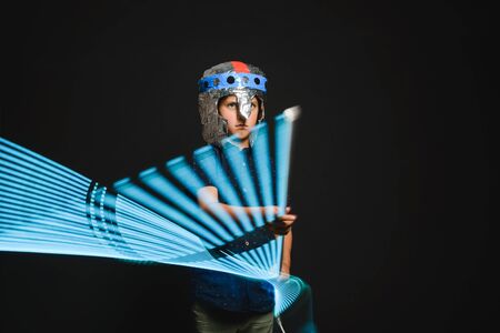 A kid with a light saber in his hands play in a superhero battle.の写真素材