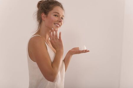 Portrait of a young attractive happy woman with a jar of cream in her hands.の写真素材