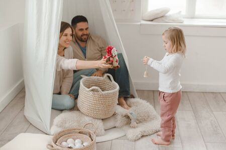 Cute baby girl with her parents play in a minimalistic childrens room.の写真素材