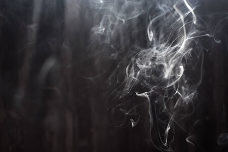 Image of backlit puffs of smoke, on a dark background.