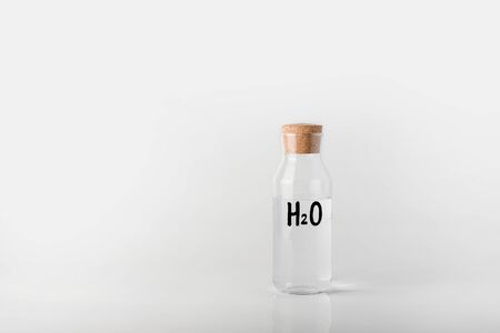 Image of a glass bottle with with the water chemical formula on it, inside which is white clear liquid.の写真素材