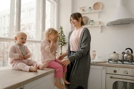 A young mother spends time with her little daughters at home.の写真素材