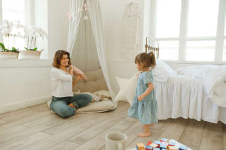A young mother spends time with her little daughter at home.
