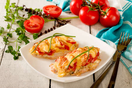 Chicken chops, fillets, baked with tomatoes and cheese on wooden backgroundの写真素材
