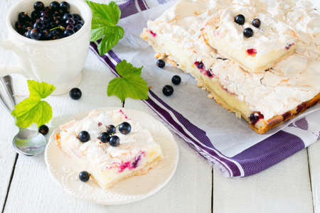 Homemade pie with meringue and black currant on a white wooden tableの写真素材