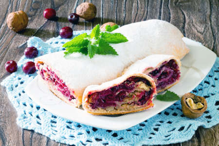 Delicious homemade cherry strudel with walnuts on a wooden backgroundの写真素材