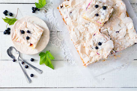 Homemade pie with meringue and black currant on a white wooden table, top viewの写真素材