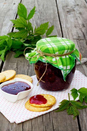 Raspberry jam in a jar on a wooden table