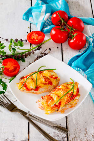 Chicken chops, fillet, baked with tomatoes and cheese on wooden backgroundの写真素材