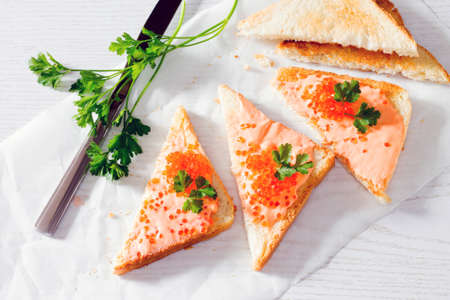 Toast with butter and salmon caviar on a wooden background